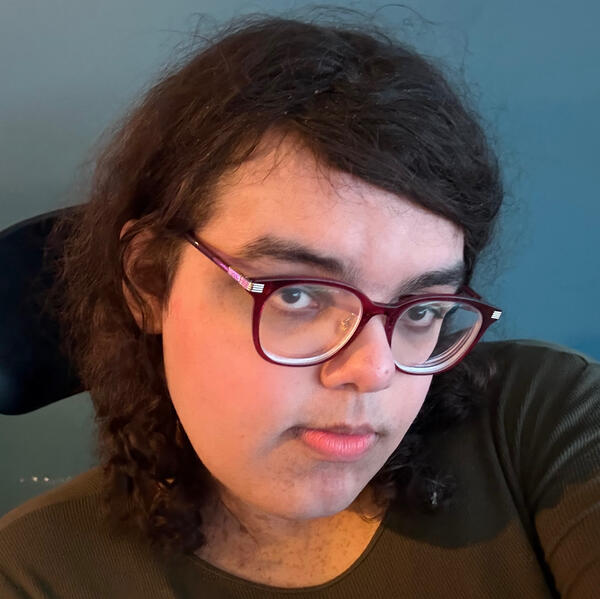 Profile This picture is of hicupalot wearing a green top and she has makeup on she is smiling in front of a green wall